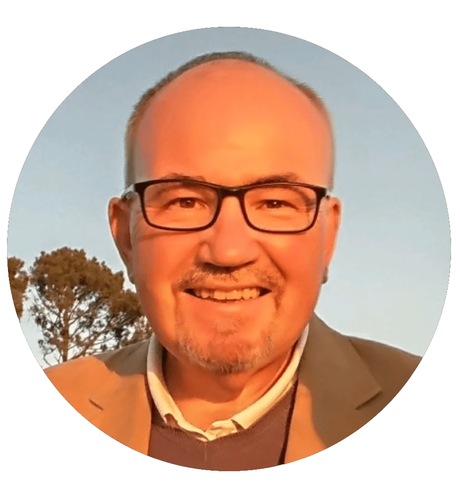 A man with a big smile, wearing glasses, a tan jacket, and a pale color button up, in flat circular cropped style image, w...